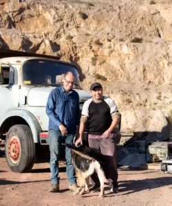 Andacollo. Vista al patio de la mina donde se hace mantenimiento de las maquinas. Se ve dos hombres y un perro enfrente de un camión.